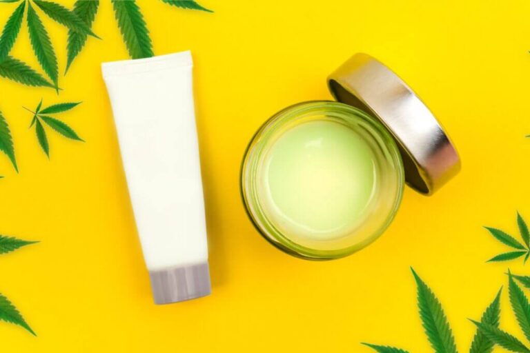 CBD-Creme mit offenem Deckel auf gelbem Hintergrund
